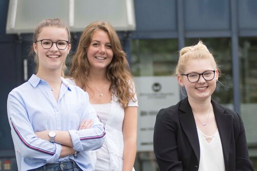 Drei junge Frauen stehen vor dem Firmengebäude