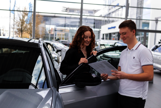 2 Azubis weiblich und Männlich stehen im Showroom des Autohauses