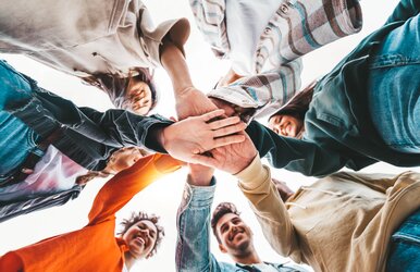 Gruppe junger Menschen legt die Hände zusammen